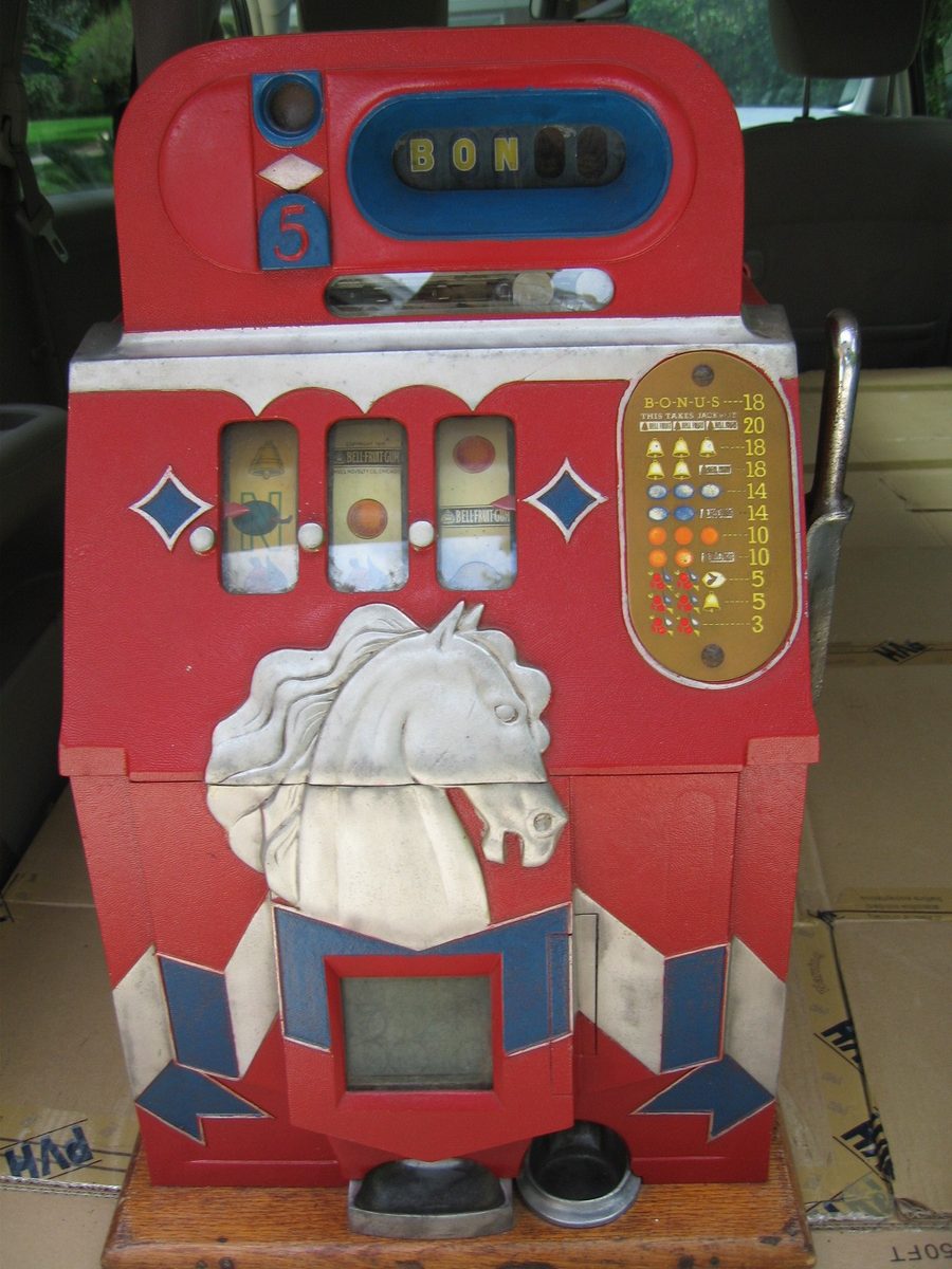 An antique red Mills Horse Head Bonus slot machine with three reels
