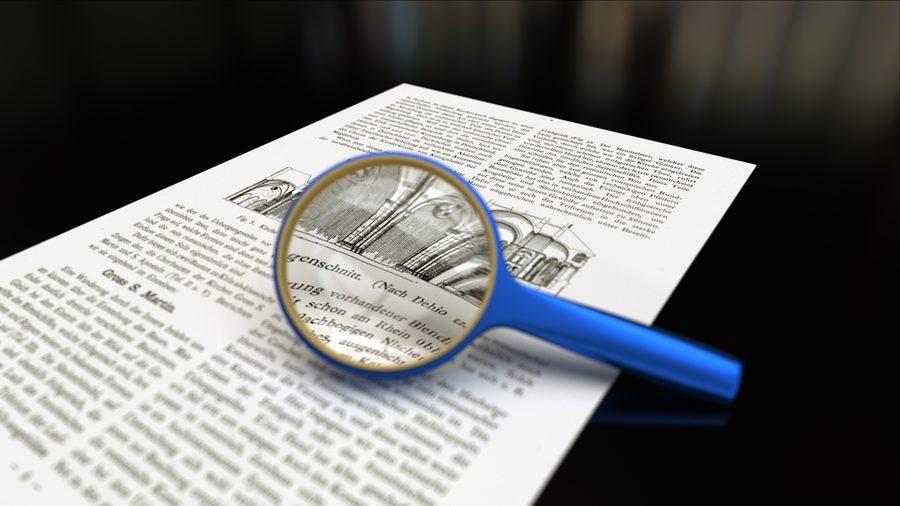 A magnifying glass resting on a printed page of small text